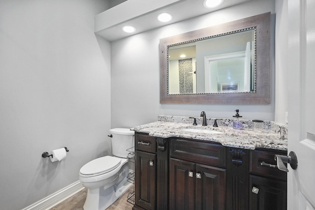 bathroom with baseboards, toilet, and vanity