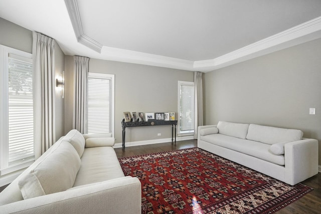 living room featuring ornamental molding, baseboards, a tray ceiling, and dark wood-style flooring