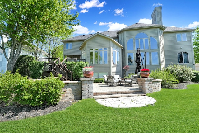 back of house featuring a lawn, stairs, and a patio area