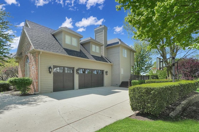 view of property exterior featuring concrete driveway, a shingled roof, a garage, brick siding, and a chimney