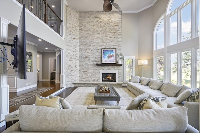 living area with baseboards, wood finished floors, a fireplace, and ornamental molding