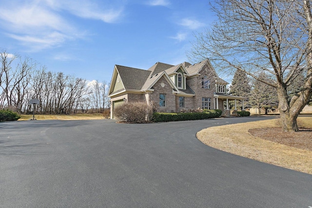 view of front of home featuring an attached garage, brick siding, driveway, and a shingled roof