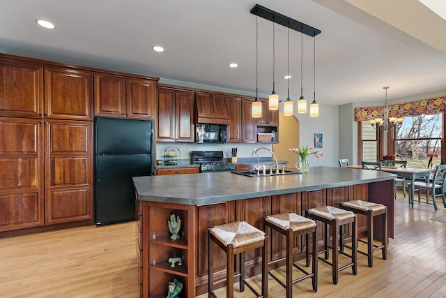 kitchen with light wood finished floors, open shelves, a sink, black appliances, and dark countertops