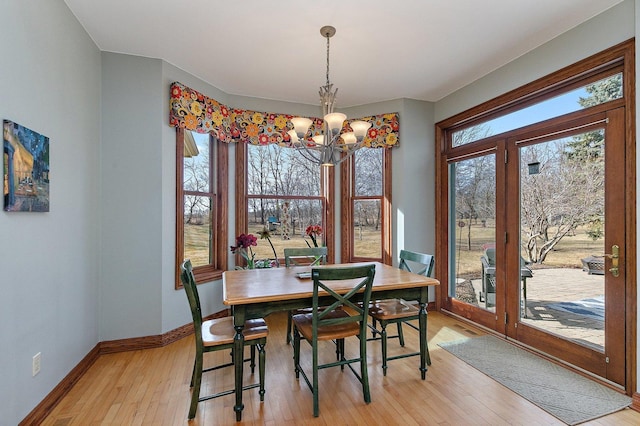 dining area featuring light wood-style floors, baseboards, and a chandelier