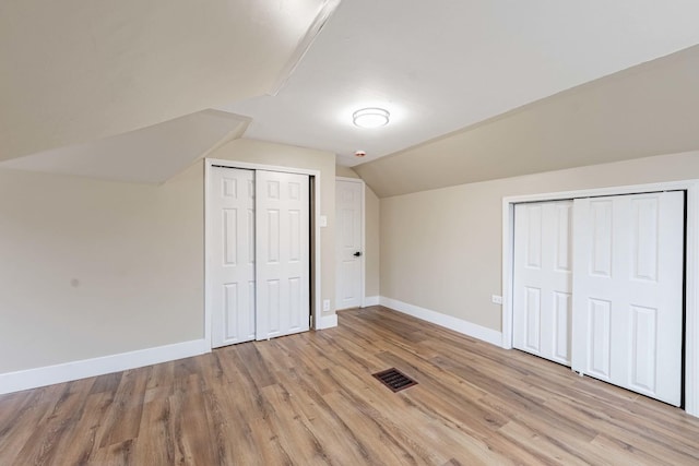 unfurnished bedroom featuring lofted ceiling, light wood-style floors, baseboards, and visible vents