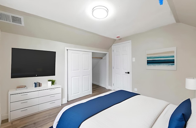 bedroom featuring lofted ceiling, a closet, visible vents, light wood-style floors, and baseboards