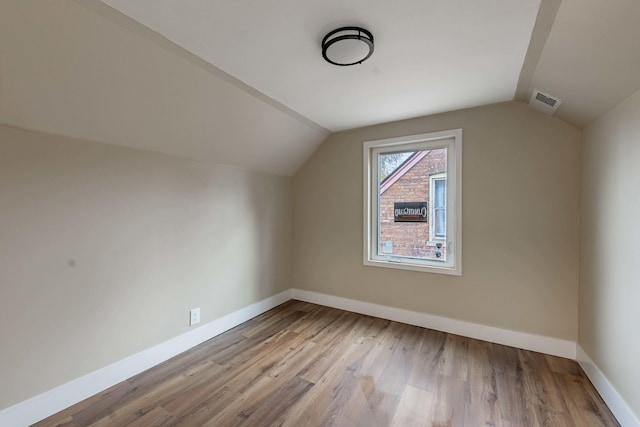 additional living space with lofted ceiling, wood finished floors, visible vents, and baseboards