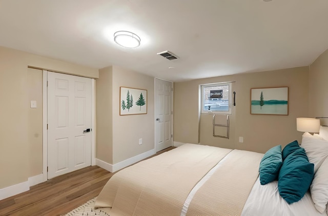 bedroom featuring visible vents, baseboards, and wood finished floors