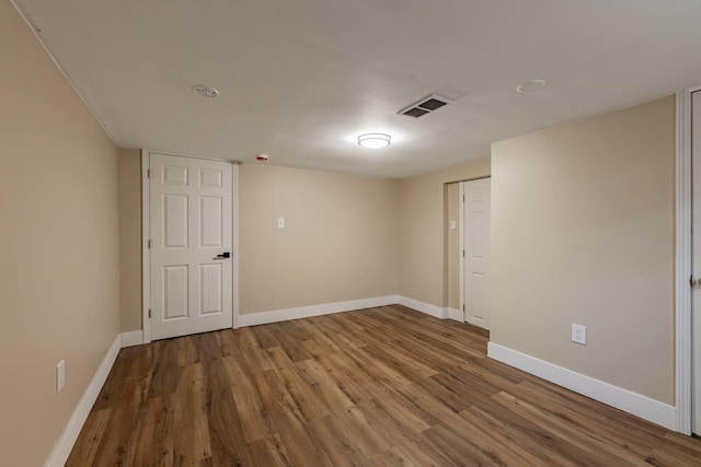 unfurnished room featuring wood finished floors, visible vents, and baseboards