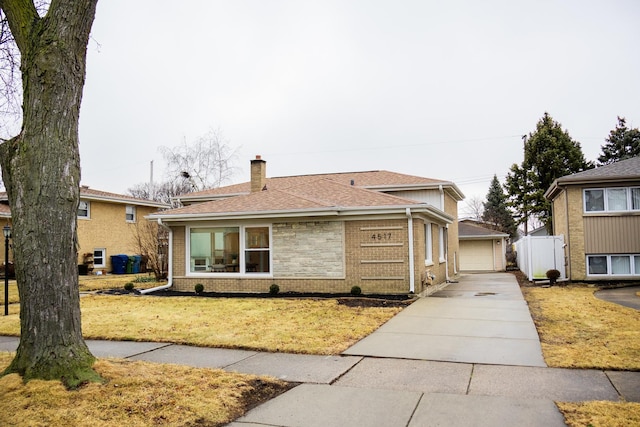 split level home with brick siding, a chimney, a front yard, and a shingled roof