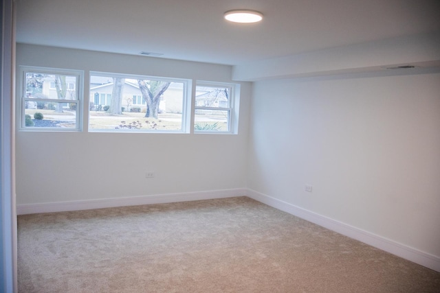 unfurnished room with light carpet, visible vents, and baseboards