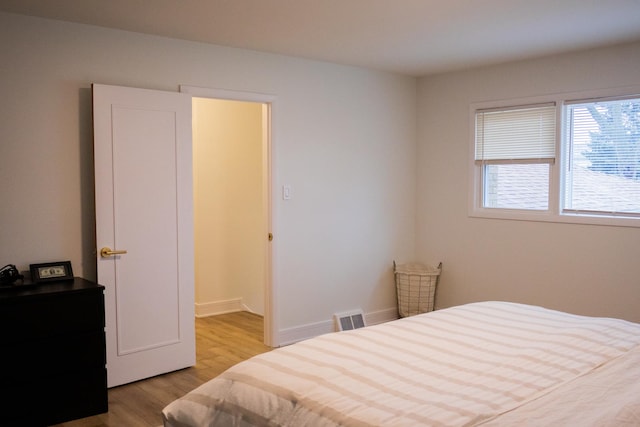 bedroom with baseboards, visible vents, and light wood-style floors