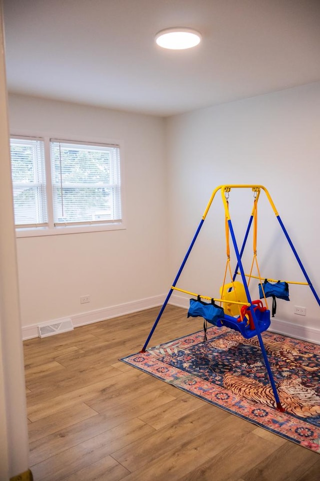 rec room with baseboards, visible vents, and wood finished floors