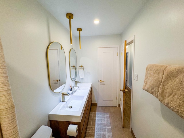 full bath featuring double vanity, baseboards, a sink, and wood finished floors