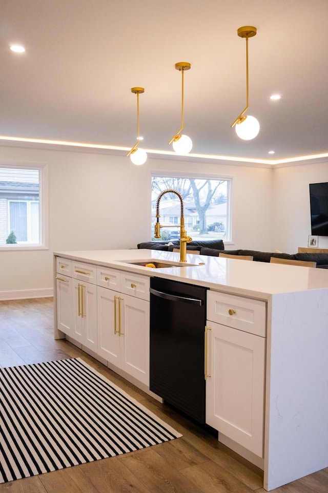 kitchen with white cabinets, dishwasher, light wood finished floors, and a sink