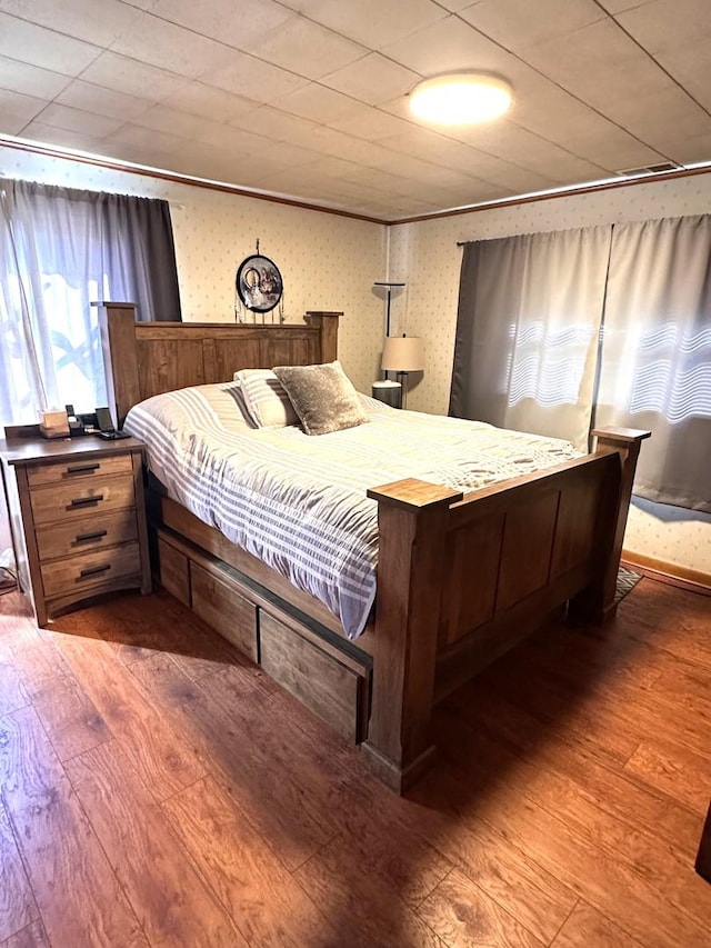 bedroom with wood finished floors and wallpapered walls