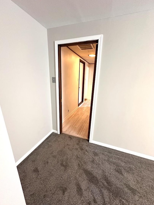 carpeted spare room featuring baseboards and visible vents