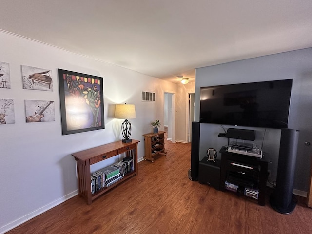 living room with baseboards, visible vents, and wood finished floors