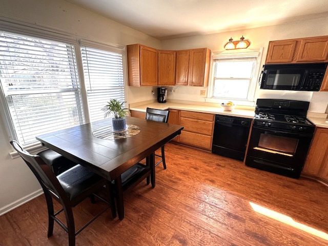 kitchen with brown cabinets, black appliances, light countertops, and wood finished floors