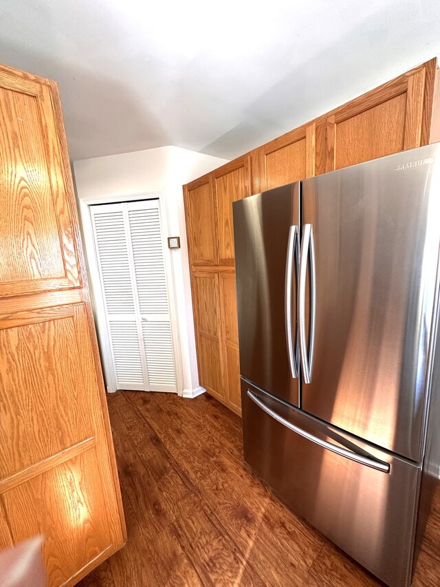 kitchen featuring freestanding refrigerator, brown cabinets, and dark wood finished floors