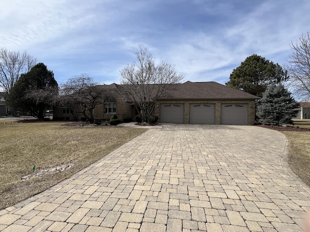 ranch-style house featuring decorative driveway, brick siding, and an attached garage