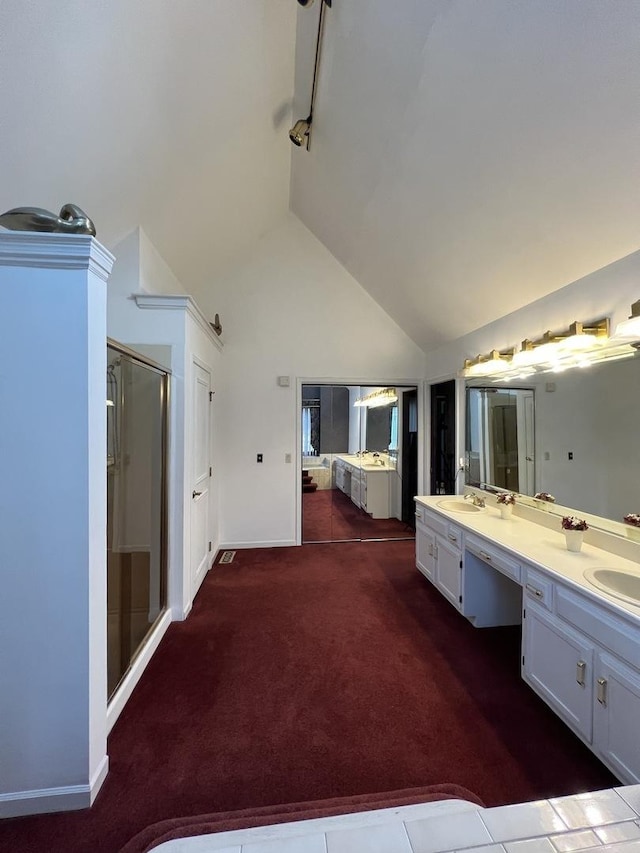 bathroom with lofted ceiling, double vanity, a stall shower, and a sink