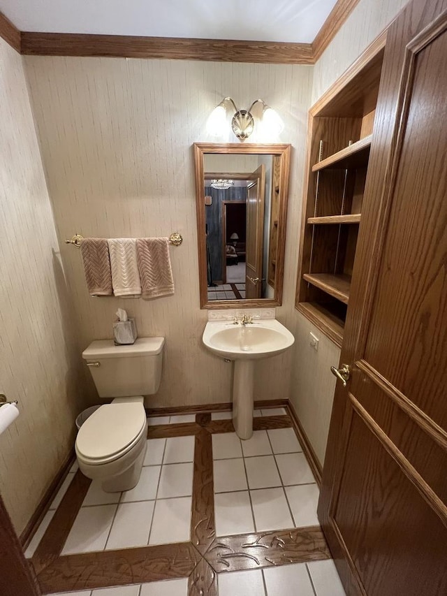 half bathroom featuring baseboards, toilet, ornamental molding, and tile patterned flooring