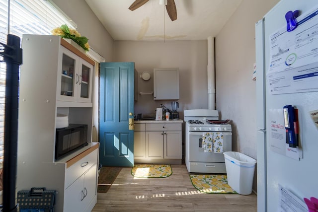 kitchen with light wood-type flooring, white appliances, light countertops, glass insert cabinets, and ceiling fan