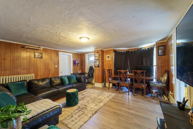 living area with wooden walls, a textured ceiling, radiator heating unit, and wood finished floors