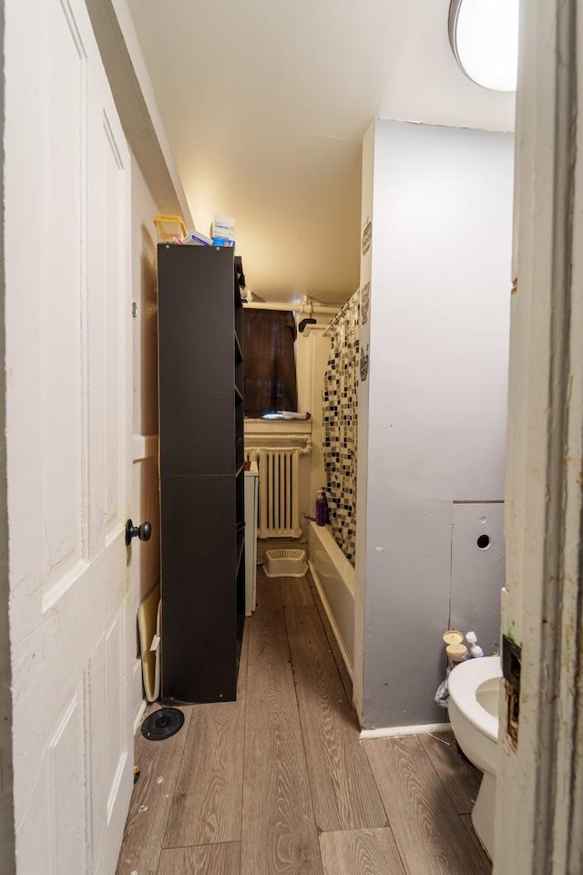 bathroom featuring toilet, radiator heating unit, wood finished floors, and shower / bath combo