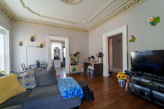 living room with crown molding, baseboards, wood finished floors, a textured ceiling, and a raised ceiling