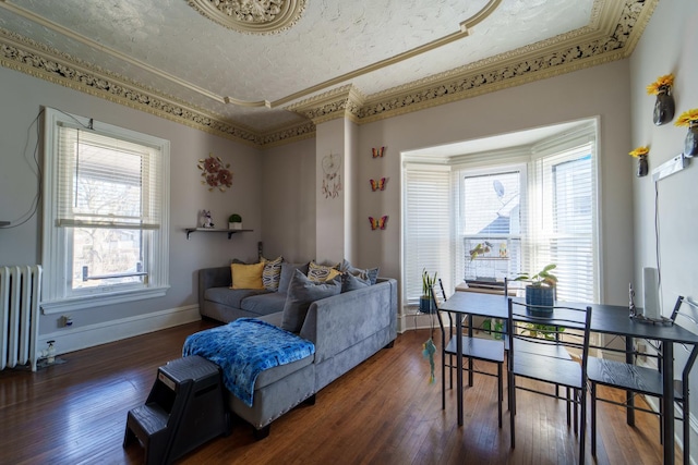 living area with ornamental molding, hardwood / wood-style flooring, a textured ceiling, radiator heating unit, and baseboards