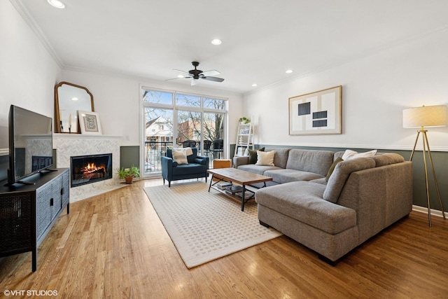 living room featuring recessed lighting, wood finished floors, a fireplace, and crown molding