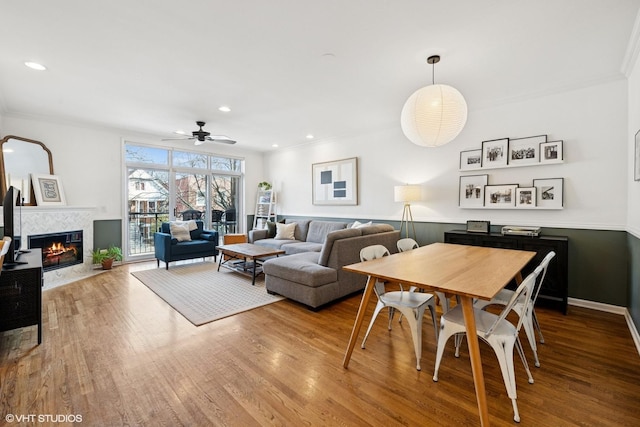 dining space featuring wood finished floors, recessed lighting, ceiling fan, a tiled fireplace, and crown molding