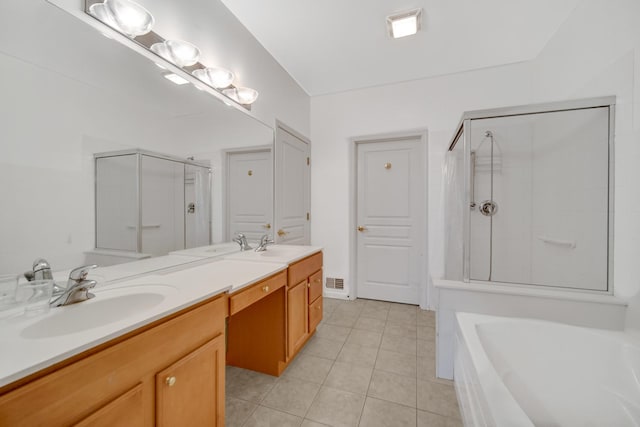 bathroom featuring a stall shower, double vanity, a sink, and tile patterned floors