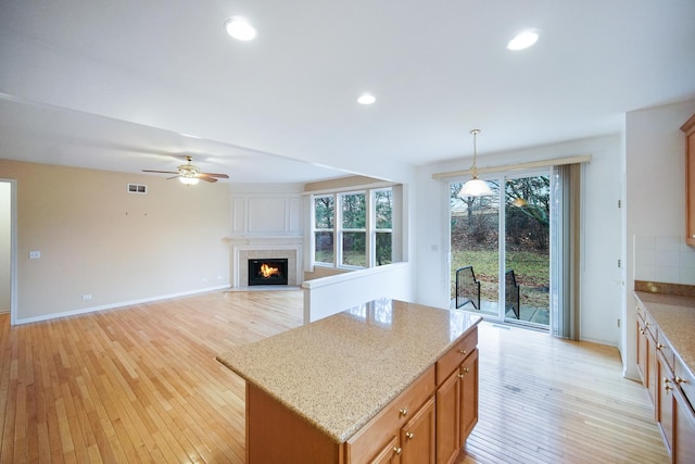 kitchen with visible vents, a fireplace with flush hearth, light stone counters, light wood-type flooring, and recessed lighting