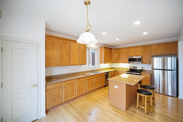 kitchen featuring a breakfast bar area, light wood-style floors, appliances with stainless steel finishes, a center island, and pendant lighting