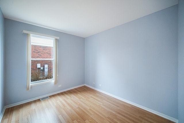 unfurnished room with light wood finished floors, baseboards, and visible vents