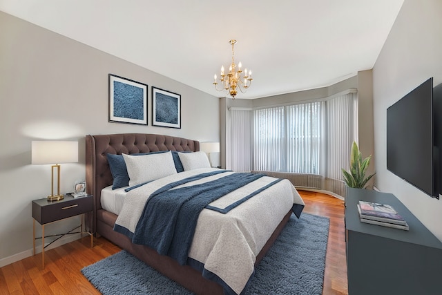 bedroom with baseboards, a chandelier, and wood finished floors