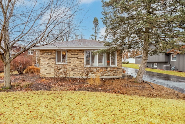 view of side of property featuring a yard, brick siding, and central AC