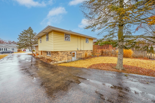 view of home's exterior with aphalt driveway, brick siding, and fence