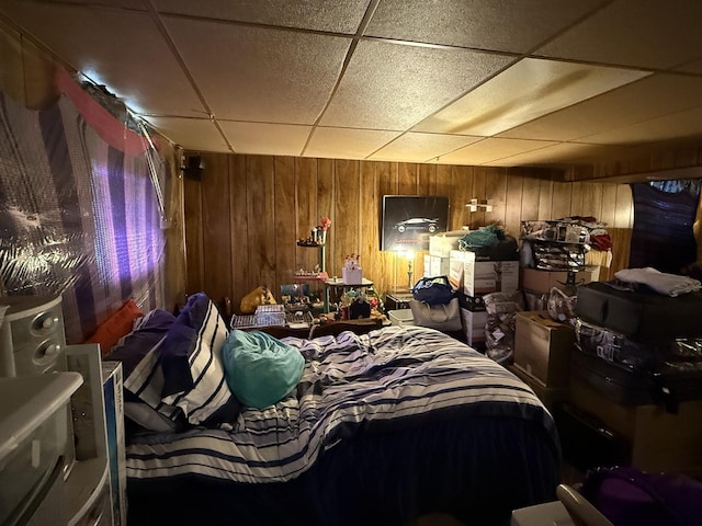 bedroom featuring a paneled ceiling and wood walls