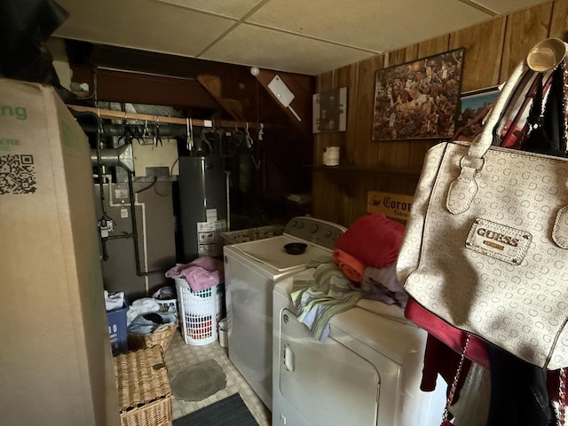 clothes washing area featuring laundry area, separate washer and dryer, gas water heater, and wooden walls