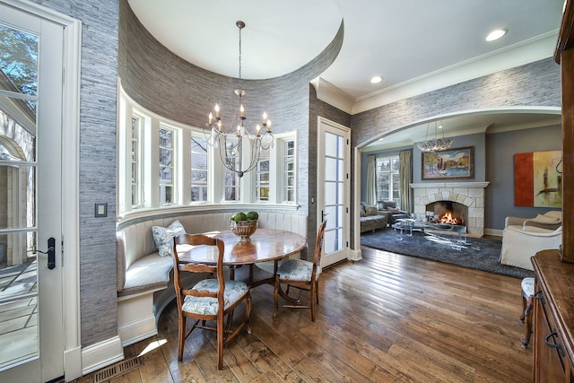 dining room featuring breakfast area, hardwood / wood-style floors, a stone fireplace, and a chandelier