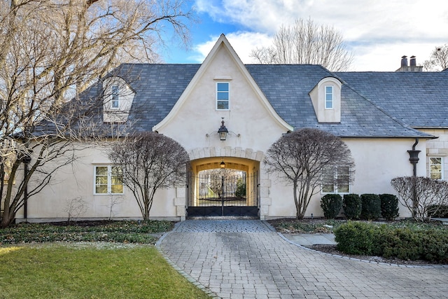 french country style house featuring stucco siding, a high end roof, and a gate