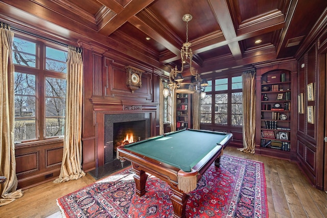 recreation room featuring a high end fireplace, wooden walls, beamed ceiling, ornamental molding, and coffered ceiling