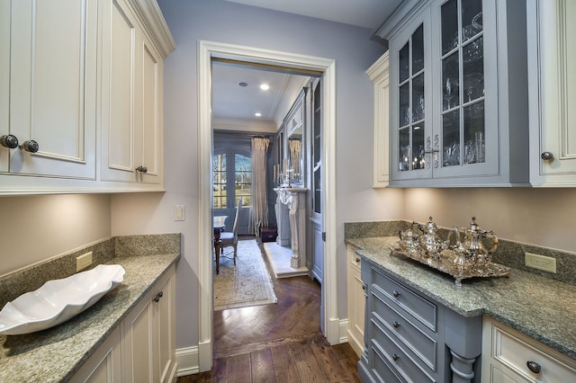 kitchen featuring dark stone countertops, glass insert cabinets, dark wood-type flooring, and recessed lighting