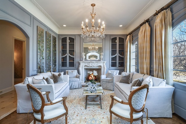 living room featuring arched walkways, a chandelier, ornamental molding, and wood finished floors