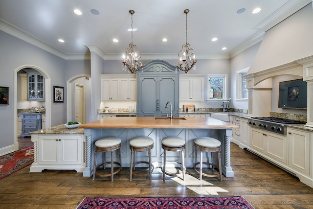 kitchen featuring dark wood-type flooring, stainless steel gas stovetop, a kitchen island with sink, and a sink