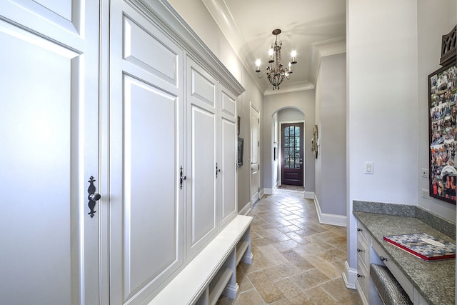 mudroom featuring ornamental molding, stone tile flooring, arched walkways, an inviting chandelier, and baseboards